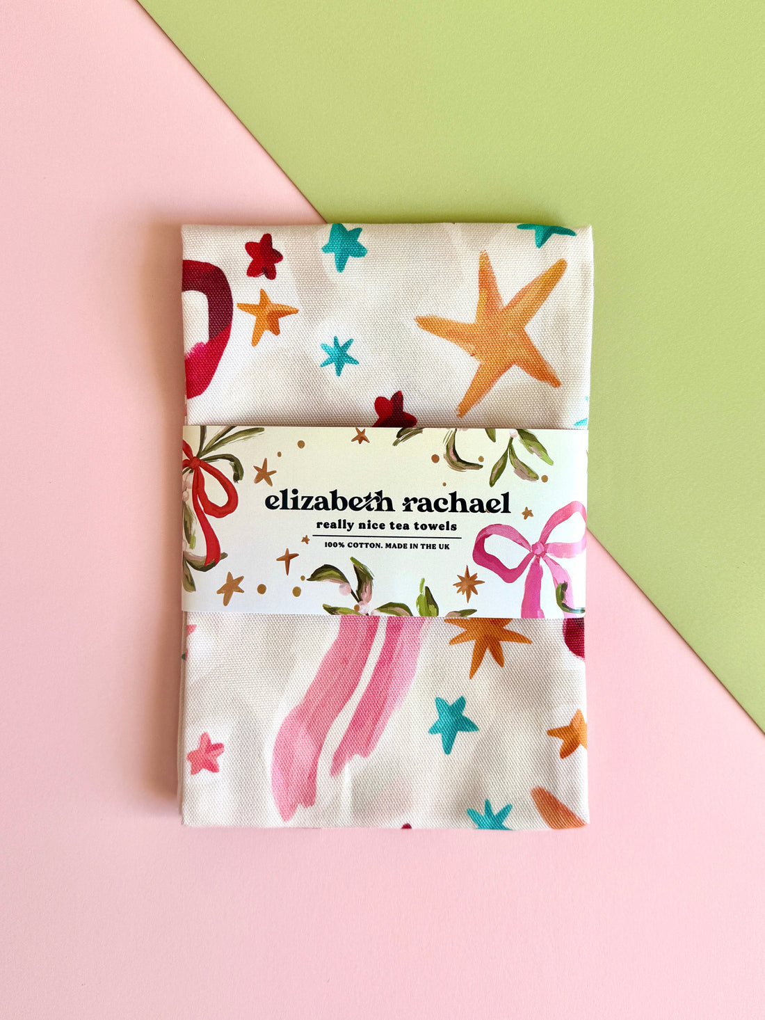 Pack of tea towels with colorful designs on a pink and green background